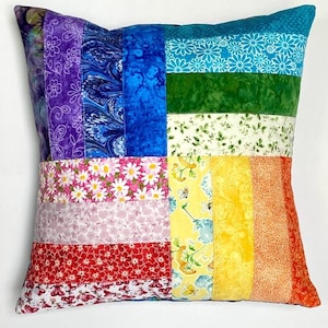 May include: A colorful patchwork pillow with a rainbow pattern. The pillow is made of different fabrics with floral and geometric designs. The pillow is a great addition to any home decor.