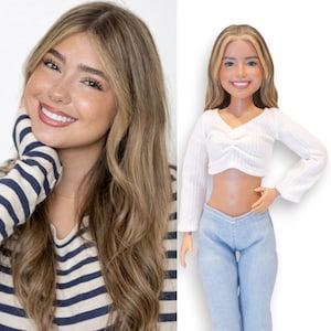 May include: A doll with long blonde hair featuring darker highlights, styled with a center part. The doll wears a white long-sleeved ribbed crop top with a gathered front detail and light blue denim pants, mirroring the appearance of the person shown.