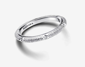 May include: A silver ring with a textured band and the word "PANDORA" engraved on the inside. The ring features small, sparkling details and geometric accents, creating a delicate and elegant design. This ring is a piece of jewelry.