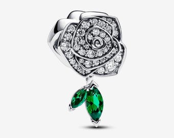 May include: A silver charm in the shape of a rose, encrusted with clear crystals. Two green, teardrop-shaped leaves dangle below the flower. The charm is designed to be a pendant or bead for a bracelet or necklace.