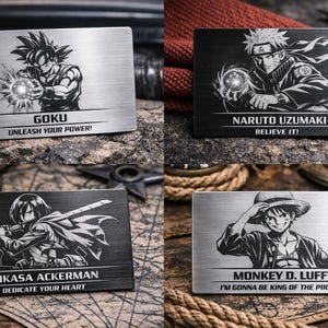 May include: Four rectangular metal plaques with engraved anime characters. Goku, Naruto Uzumaki, Mikasa Ackerman, and Monkey D. Luffy are shown with text below. Phrases include "Unleash Your Power!" and "Believe It!" on the plaques.