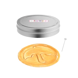 May include: A silver tin with a colorful logo that says "Dalgona Challenge" and a round, golden brown dalgona candy with a dolphin shape pressed into it. A silver metal skewer is also included.