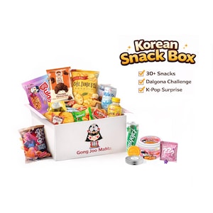 May include: A white box filled with various Korean snacks, including chips, candies, and drinks. The box is labeled "Gong Joo MaMa" and "Korean Snack Box." The image also includes a can of soda, a small bottle of juice, and a Dalgona candy.