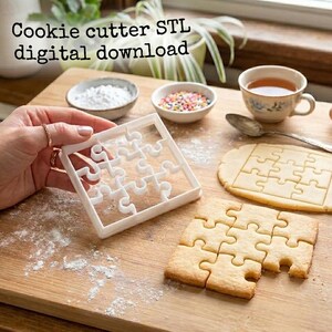 May include: A white square puzzle-shaped cookie cutter made for 3D printing, accompanied by a sheet of rolled dough and baked cookies cut into puzzle pieces. The text "Cookie cutter STL digital download" is visible at the top of the image.