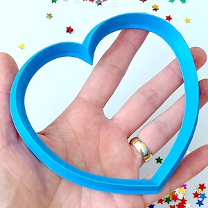Pode incluir: Um cortador de biscoitos em forma de coração de plástico azul brilhante.