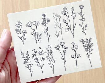 May include: A sheet of white paper with black line drawings of various flowers and plants. The drawings are simple and delicate, and they would be perfect for use in a scrapbook or journal.