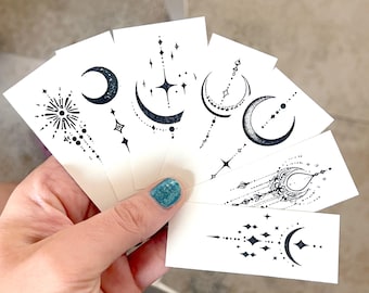 May include: Set of eight small temporary tattoos featuring celestial designs with moons and stars. The tattoos are printed on white paper.