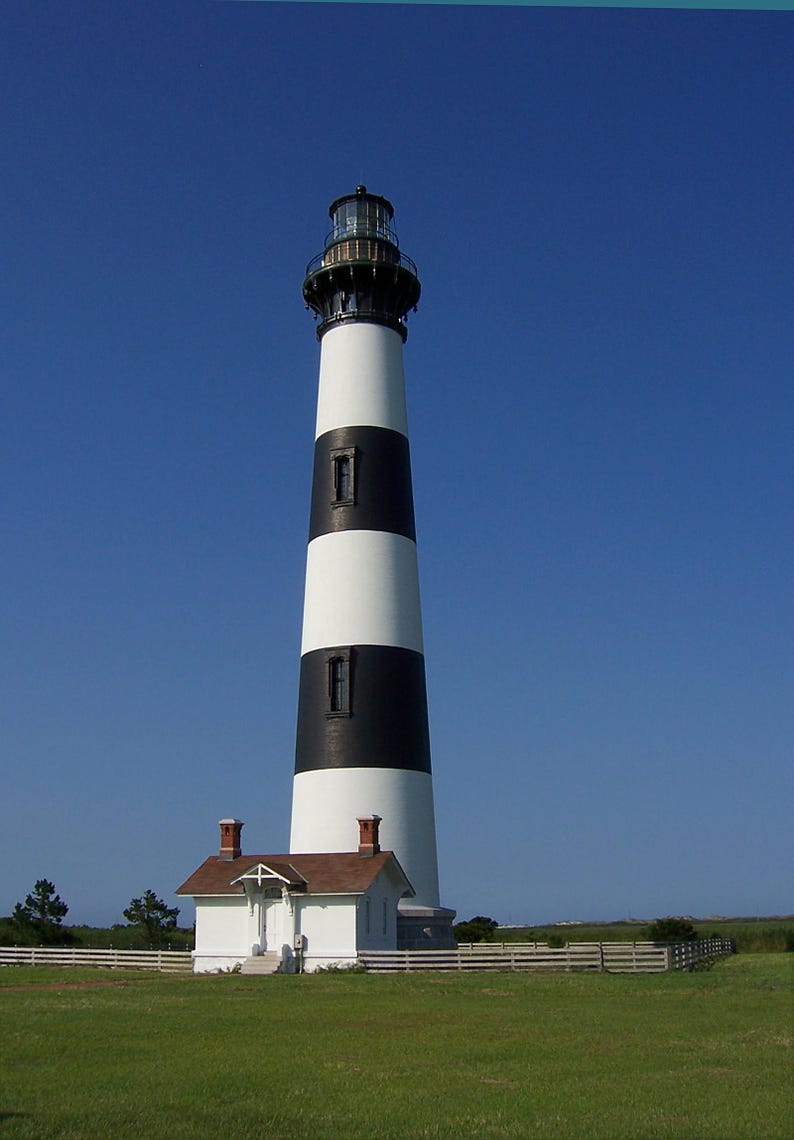 K&ouml;nnte beinhalten: Ein hoher, konischer Leuchtturm mit abwechselnden horizontalen schwarzen und wei&szlig;en Streifen. Das Bauwerk ist mit einer gl&auml;sernen Laterne gekr&ouml;nt und verf&uuml;gt an der Basis &uuml;ber ein kleines, wei&szlig;es einst&ouml;ckiges Geb&auml;ude mit braunem Dach.