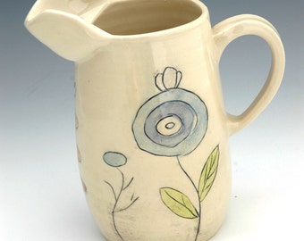 Handmade white pottery pitcher with flowers and unique design