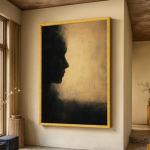 May include: A large framed artwork featuring a profile silhouette in black against a golden-beige background. The artwork is enclosed in a gold-colored frame, adding a touch of elegance to the piece. The overall aesthetic is minimalist and modern.