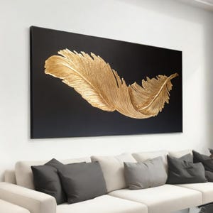 Puede incluir: Una gran pluma dorada sobre un fondo negro. La pluma es 3D y tiene una superficie texturizada.