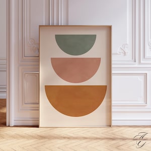 Könnte beinhalten: Ein gerahmter Kunstdruck mit drei halbkreisförmigen Formen in gedämpften Farben: Salbeigrün, Staubrosa und gebranntes Orange. Das Kunstwerk ist vor einem cremefarbenen Hintergrund platziert und in einem hellen Holzton gerahmt.