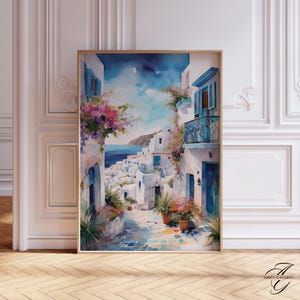 Puede incluir: Pintura a la acuarela de un pueblo costero con edificios blancos, contraventanas azules y flores vibrantes. La obra de arte está enmarcada en un marco de madera dorado. La escena representa un día soleado con vistas al mar.