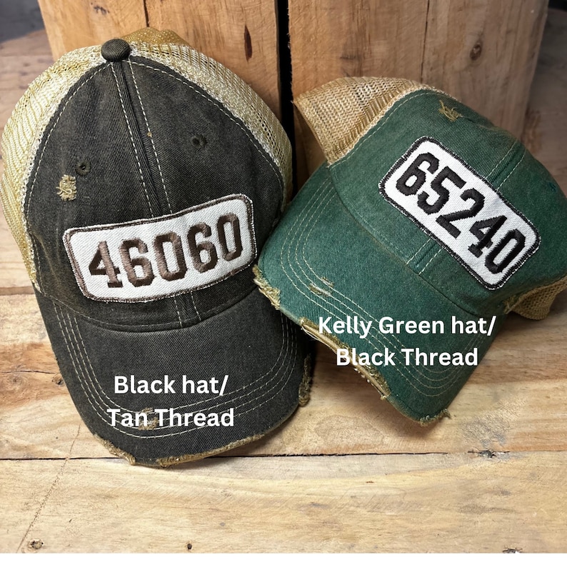 May include: Two trucker hats with distressed fabric and mesh panels. The black hat has tan thread and the number 46060 on the front. The kelly green hat has black thread and the number 65240 on the front.