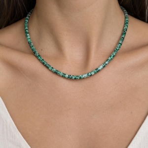 May include: A necklace composed of small, cylindrical beads in varying shades of emerald green and white. The beads feature a mottled, marbled texture throughout, creating a consistent pattern along the entire length of the circular strand.
