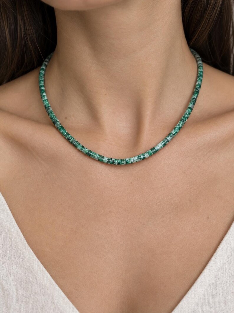 May include: A necklace composed of small, cylindrical beads in varying shades of emerald green and white. The beads feature a mottled, marbled texture throughout, creating a consistent pattern along the entire length of the circular strand.