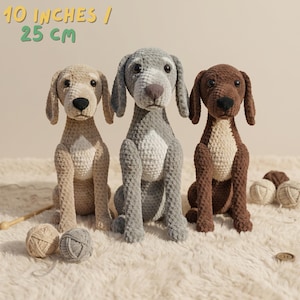 May include: Three crocheted dog plushies in beige, gray, and brown, each approximately 10 inches (25 cm) tall. The dogs have floppy ears, black eyes, and are sitting upright. The text "10 INCHES / 25 CM" is at the top. Yarn balls are in the foreground.
