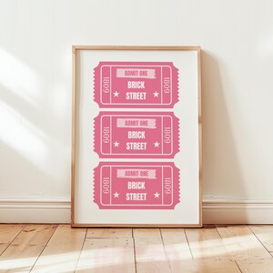 Op de afbeelding: Een ingelijst print met drie roze tickets waarop op elk ticket "1809 Admit One Brick Street 1809" staat.