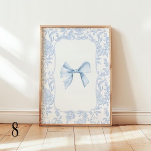 May include: A framed art print featuring a light blue watercolor bow on a white background. The frame is surrounded by a floral pattern in light blue. The artwork is displayed in a wooden frame, adding a touch of elegance to the piece.