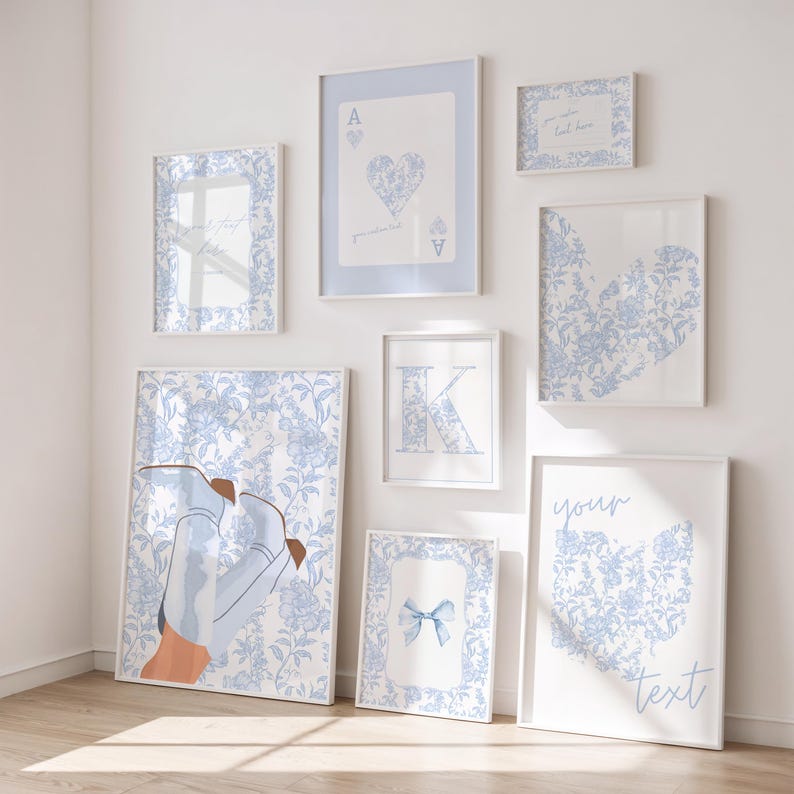 May include: A collection of framed art prints in various sizes, featuring a consistent light blue and white floral pattern. The prints include a playing card, a heart, the letter "K", a bow, and text. The largest print depicts a pair of boots.