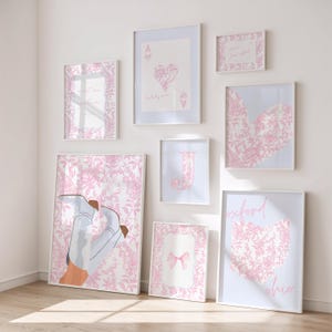 May include: A collection of framed art prints in various sizes, featuring a consistent pink and white color scheme. The prints include floral patterns, playing card designs, a bow, a heart-shaped Ohio outline, and the letter "J".
