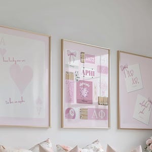 Puede incluir: Tres impresiones artísticas enmarcadas con marcos dorados. Las impresiones presentan una combinación de colores rosa y blanco con texto y gráficos. Una impresión tiene un corazón y el texto "how lucky are we to be in aphi".