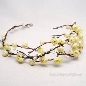 May include: A delicate floral crown with yellow blossoms and brown branches. The crown is made of artificial flowers and is perfect for a wedding or special occasion.