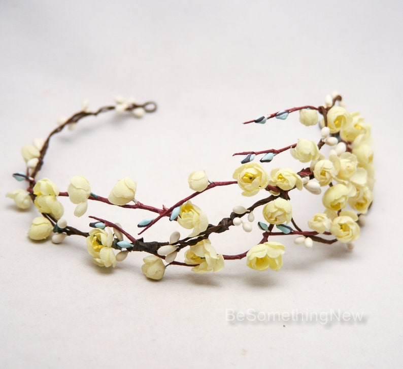 May include: A delicate floral crown with yellow blossoms and brown branches. The crown is made of artificial flowers and is perfect for a wedding or special occasion.
