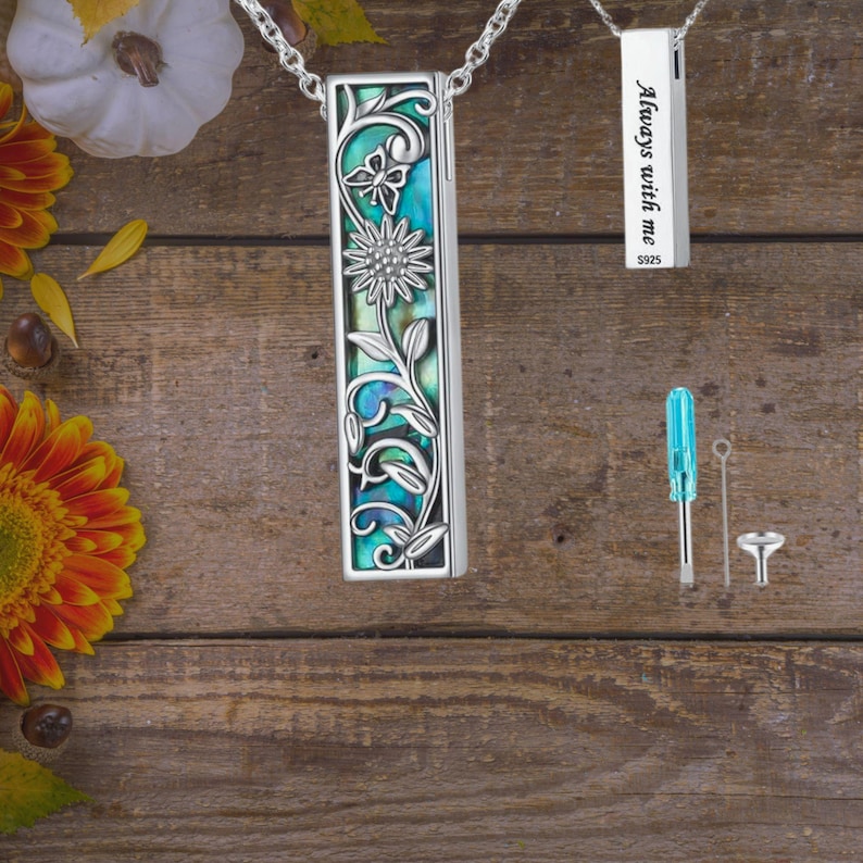 May include: Silver rectangular pendant necklace with floral and butterfly design, featuring turquoise and abalone-like inlays. A second pendant reads "Always with me". Includes tools for assembly.