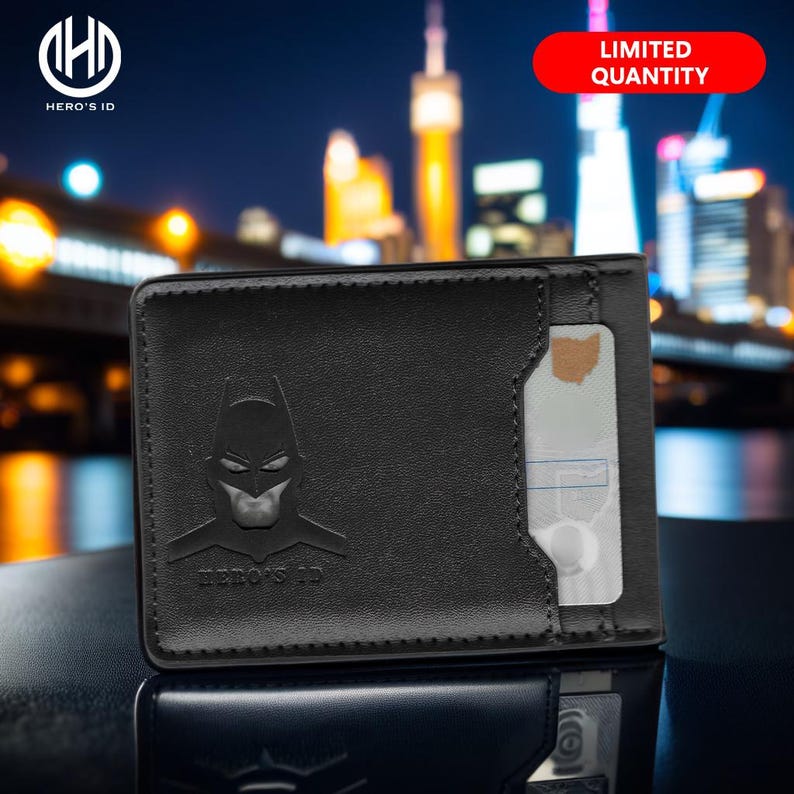 May include: Black leather wallet with a Batman logo embossed on the front. The wallet has a card slot on the right side and the text "HERO'S ID" is printed below the logo.