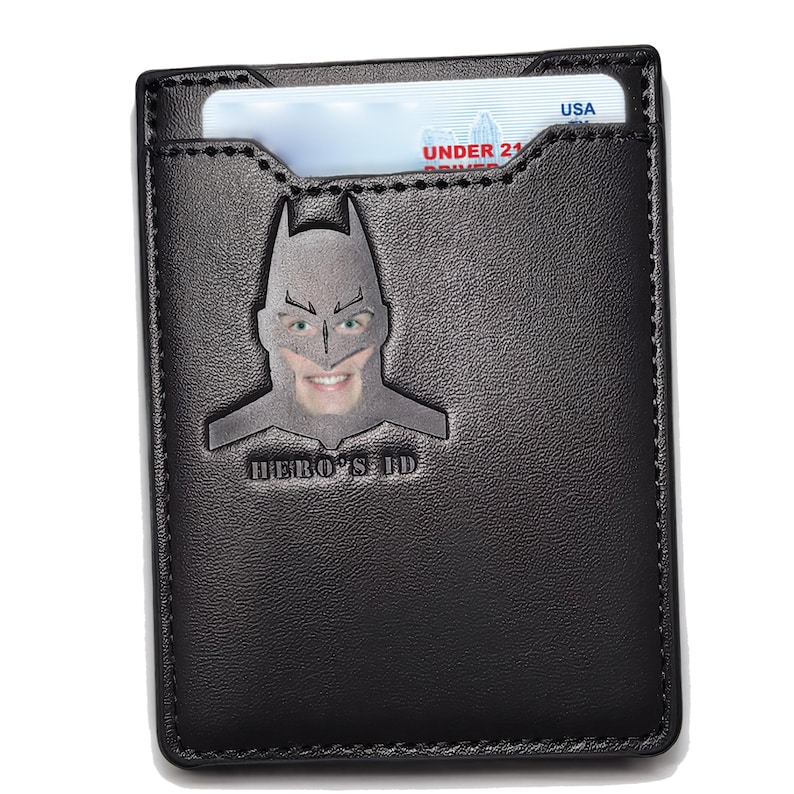 May include: Black leather wallet with a Batman silhouette and the text "HERO'S ID". The wallet has a slot for a card or ID.
