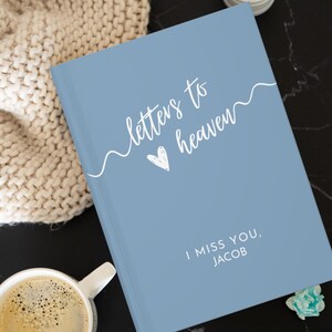 May include: A blue journal with the text "letters to heaven" in white cursive script with a heart symbol. The text "I miss you, JACOB" is also in white.