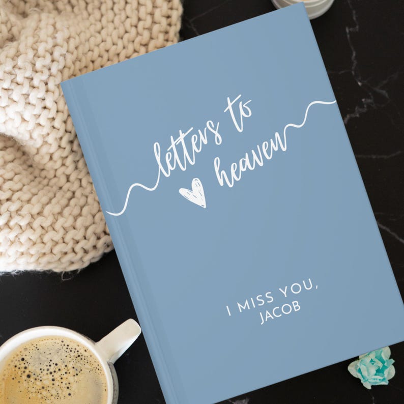May include: A blue journal with the text "letters to heaven" in white cursive script with a heart symbol. The text "I miss you, JACOB" is also in white.