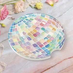 May include: A colorful, round coaster with a mosaic design resembling a disco ball. The coaster is made of ceramic and has a cutout for a beverage.