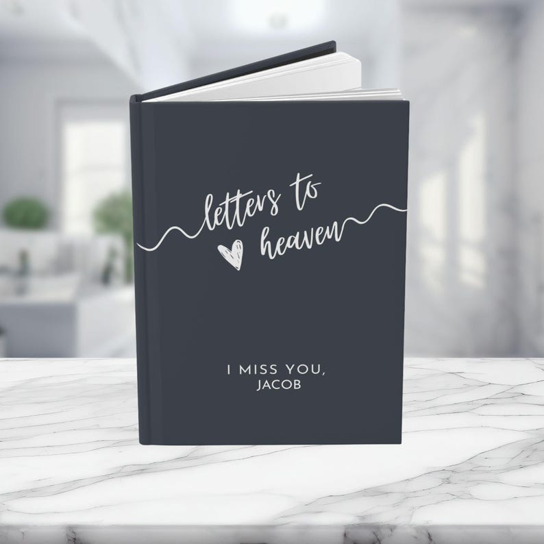 May include: A dark gray journal with the text "letters to heaven" and a heart symbol. The text "I miss you, Jacob" is printed below the title.