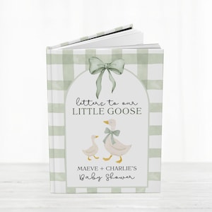 May include: A baby shower guest book with a green gingham pattern cover. The cover features a watercolor illustration of two geese and the text "Letters to our Little Goose". The book is open, revealing blank pages.