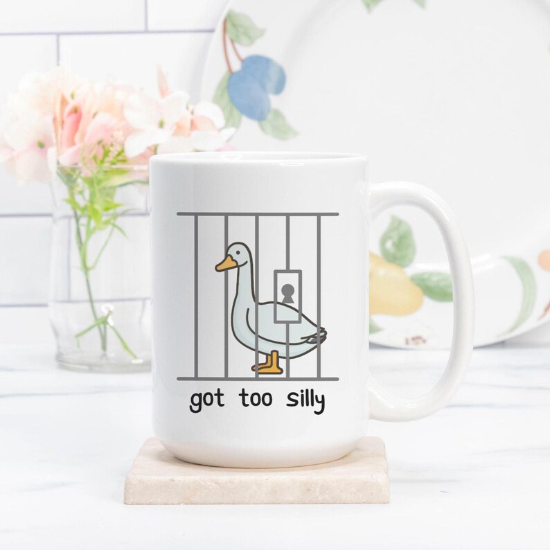 May include: White ceramic mug with a cartoon illustration of a goose in a jail cell. The text "got too silly" is printed below the image.