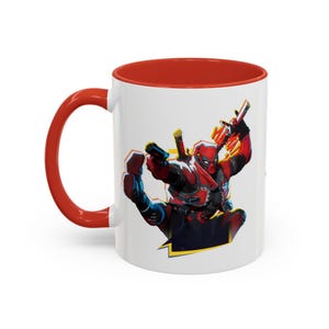 Può includere: Tazza in ceramica bianca con interno e manico rossi. La tazza presenta un'illustrazione dinamica di Deadpool in tuta rossa e nera, con pistole. Il design ha accenti gialli e blu.