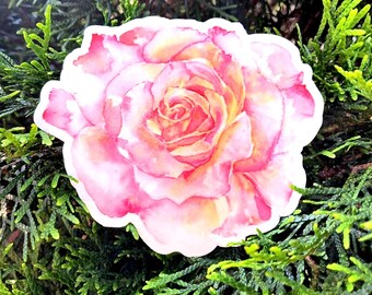 May include: A sticker featuring a watercolor painting of a pink and yellow rose. The rose is in full bloom, with detailed petals and a soft, blended color palette. The sticker is set against a backdrop of green foliage.