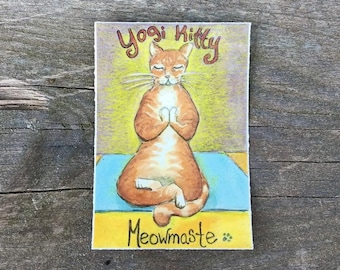 May include: A watercolor painting of an orange cat in a yoga pose on a blue mat. The text "Yogi Kitty" is above the cat, and "Meowmaste" is below. The background is yellow.