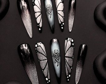Uñas postizas góticas con diseño de mariposa: uñas con efecto stiletto en degradado negro y plateado con diseños de luna y alas
