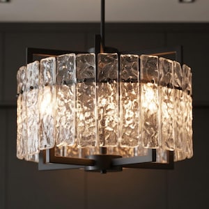 May include: A modern chandelier with a square, black metal frame. The fixture features rectangular, textured glass panels that surround the light source. The glass panels have a frosted appearance, and the overall design is contemporary.