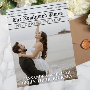 May include: A wedding-themed newspaper cover titled "The Newlywed Times" with the headline "Wedding of the Year." The cover features a photo of a couple on a beach. The text reads "Cassandra and Elijah Begin Their Journey."
