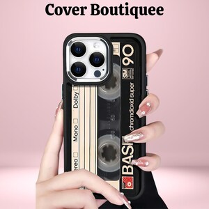 May include: Black phone case with a retro cassette tape design. The case features a black border and a beige cassette tape graphic with the text "BASF 90 chromdioxid super". The text "Cover Boutiquee" is at the top.