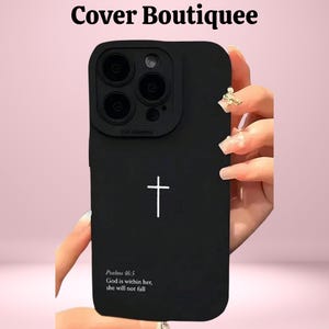 Puede incluir: Funda de teléfono negra con un diseño de cruz blanca y el texto "Salmos 46:5 Dios está en ella, no caerá." La funda tiene un acabado mate y un recorte para la cámara. La marca "Cover Boutiquee" está en la parte superior.