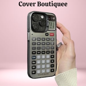 May include: A silver and black phone case with a calculator design. The case has a screen displaying numbers and buttons for calculations. The text "Cover Boutiquee" is at the top. The phone case is held by a hand.