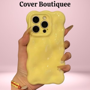 May include: A yellow phone case with a unique, wavy design. The case has a glossy finish and features cutouts for the phone's camera lenses. The text "Cover Boutiquee" is visible at the top of the image.