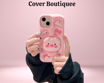 May include: Pink phone case with a pig design. The case features a 3D pig face, clouds, and bows. The text "Pig" is visible on the case. The words "Cover Boutiquee" are at the top of the image.
