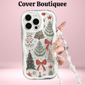 May include: Clear phone case featuring a festive Christmas tree design with red bows and stars. The case has a white background and a clear border. A beaded strap with clear charms is attached. The text "Cover Boutiquee" is at the top.