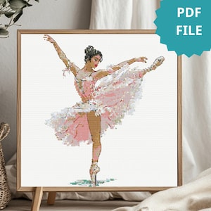May include: A framed cross-stitch of a ballerina in a pink tutu, arms outstretched, en pointe. The artwork is in a wooden frame and includes the text "PDF FILE" in a teal circle. The ballerina is depicted in a graceful pose.